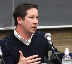 A man in a sweater speaking to a group